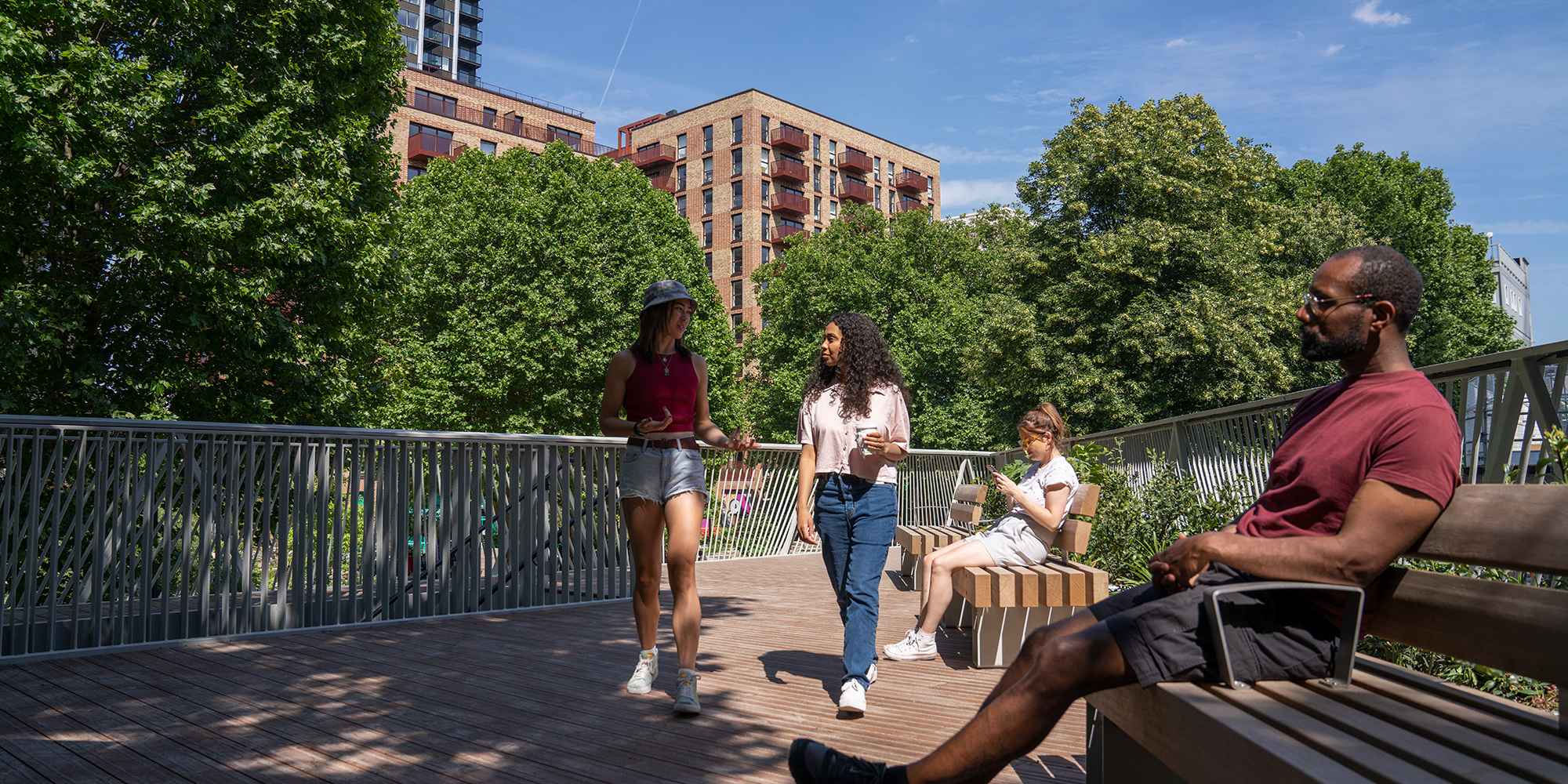 A man sitting on a bench on the Tree House balcony while women walk past.